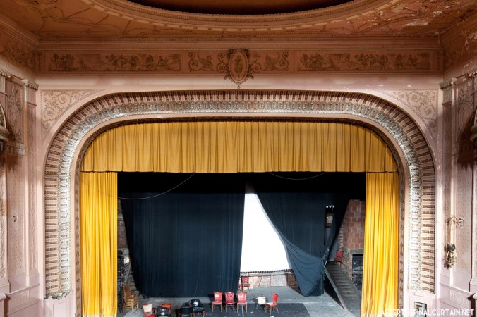 The Proscenium arch is surrounded by beaded plaster molding and a motif of acanthus leaves. At the center is the figure of a girl that is repeated throughout the plaster-work of the theater.