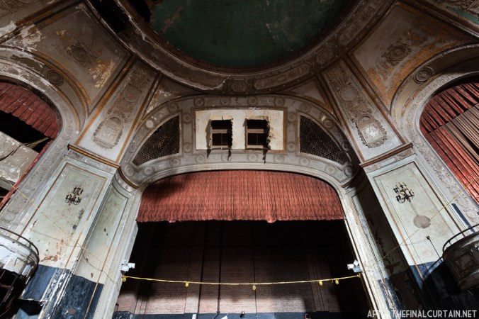 The proscenium has two large holes in it due to the removal of sound or lighting equipment after the theater closed.